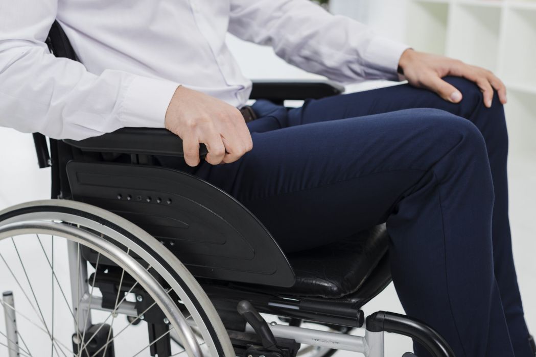 A realistic side-view scene of a sad businessman sitting alone in a wheelchair in a hospital setting, conveying the long-term physical and emotional impact of a catastrophic injury, representing the types of life-changing injury cases handled by a Framingham catastrophic injury lawyer.