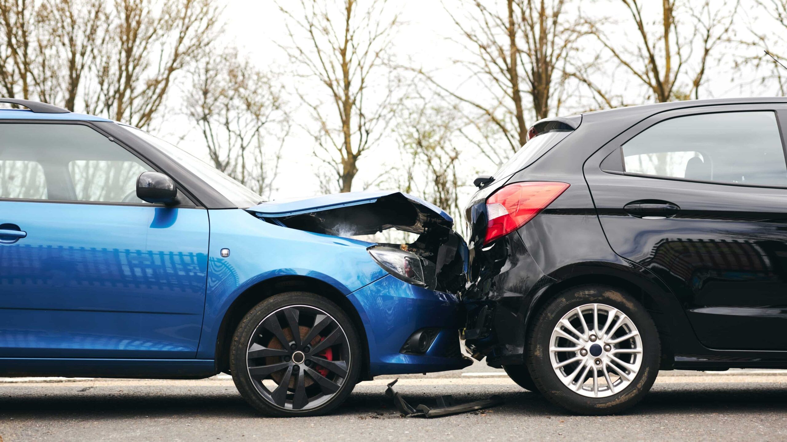 Accidente automovilístico por alcance en el que un vehículo azul chocó contra un SUV negro, mostrando daños importantes en la parte delantera y trasera.