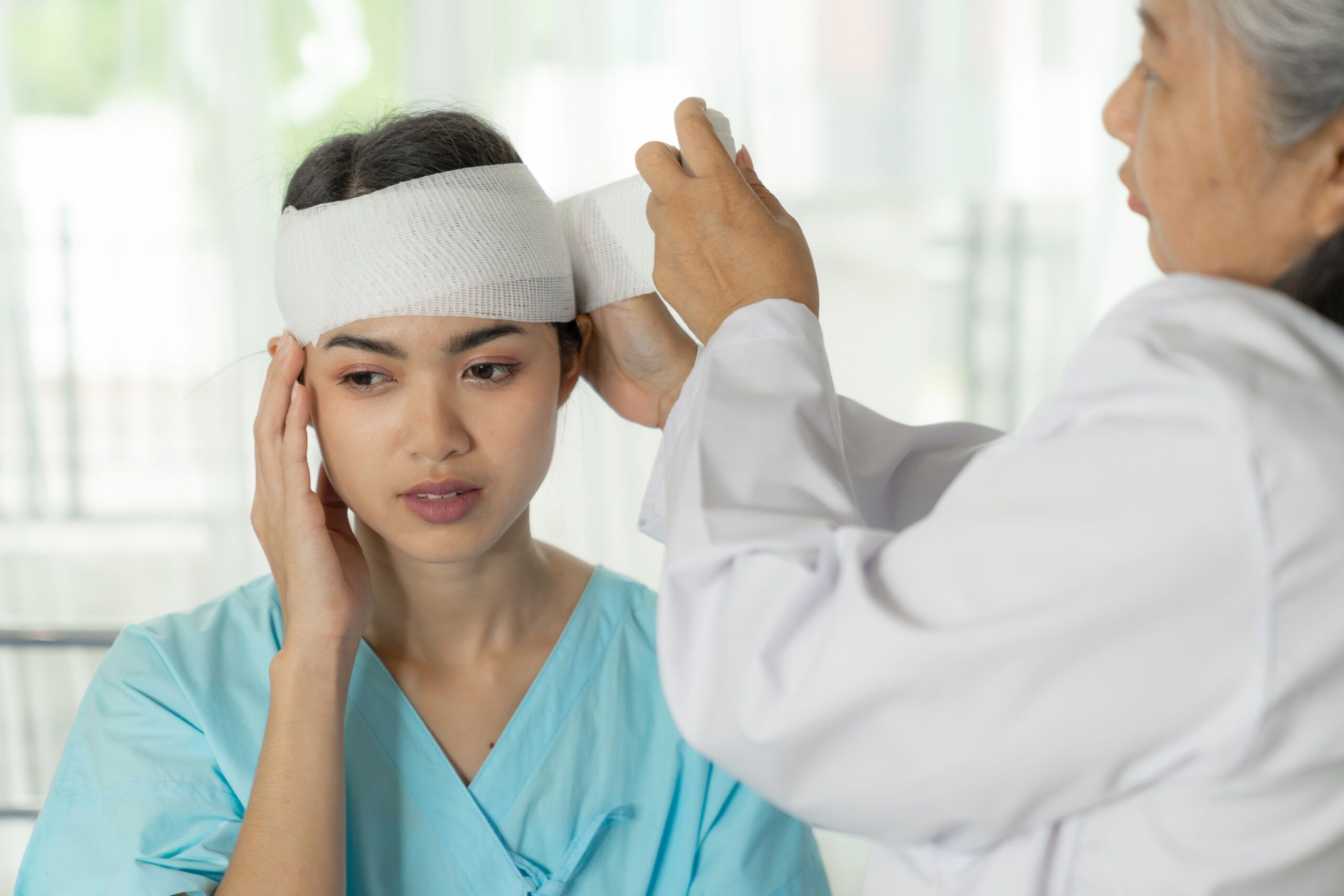 Uma cena fotorrealista de um paciente em um hospital com um ferimento na cabeça enfaixado, representando os tipos de casos de lesão cerebral traumática atendidos por um advogado especializado em lesões cerebrais de Revere.