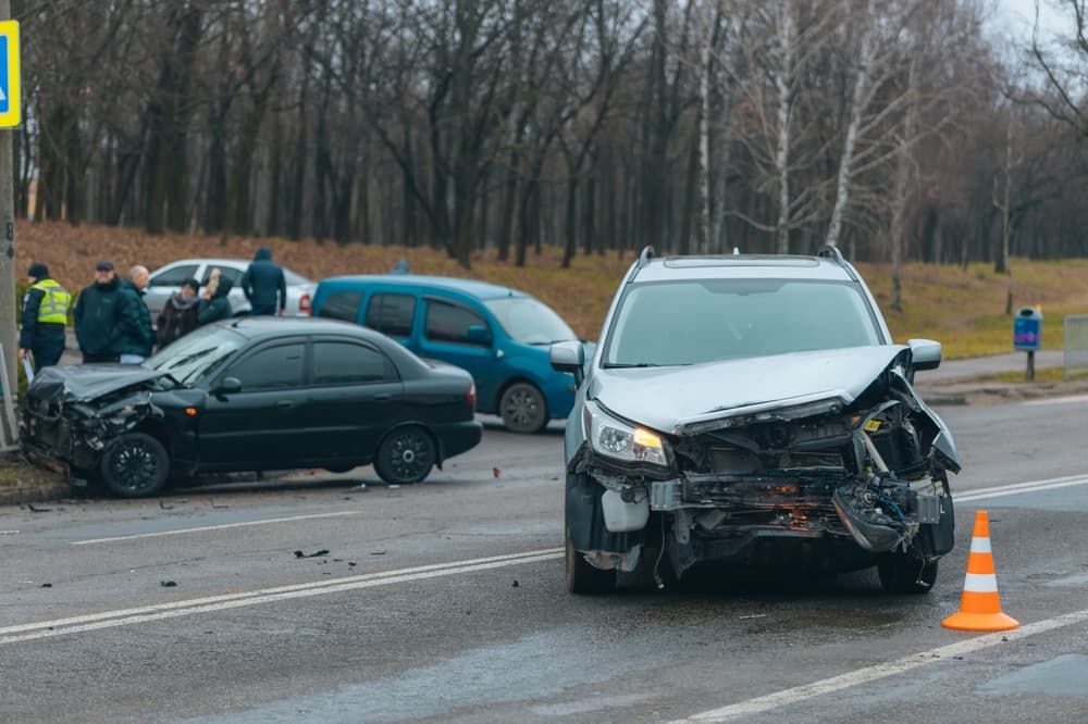 A serious car accident on a roadway, showing damaged vehicles, traffic cones, police presence, and hazardous road conditions contributing to the crash.