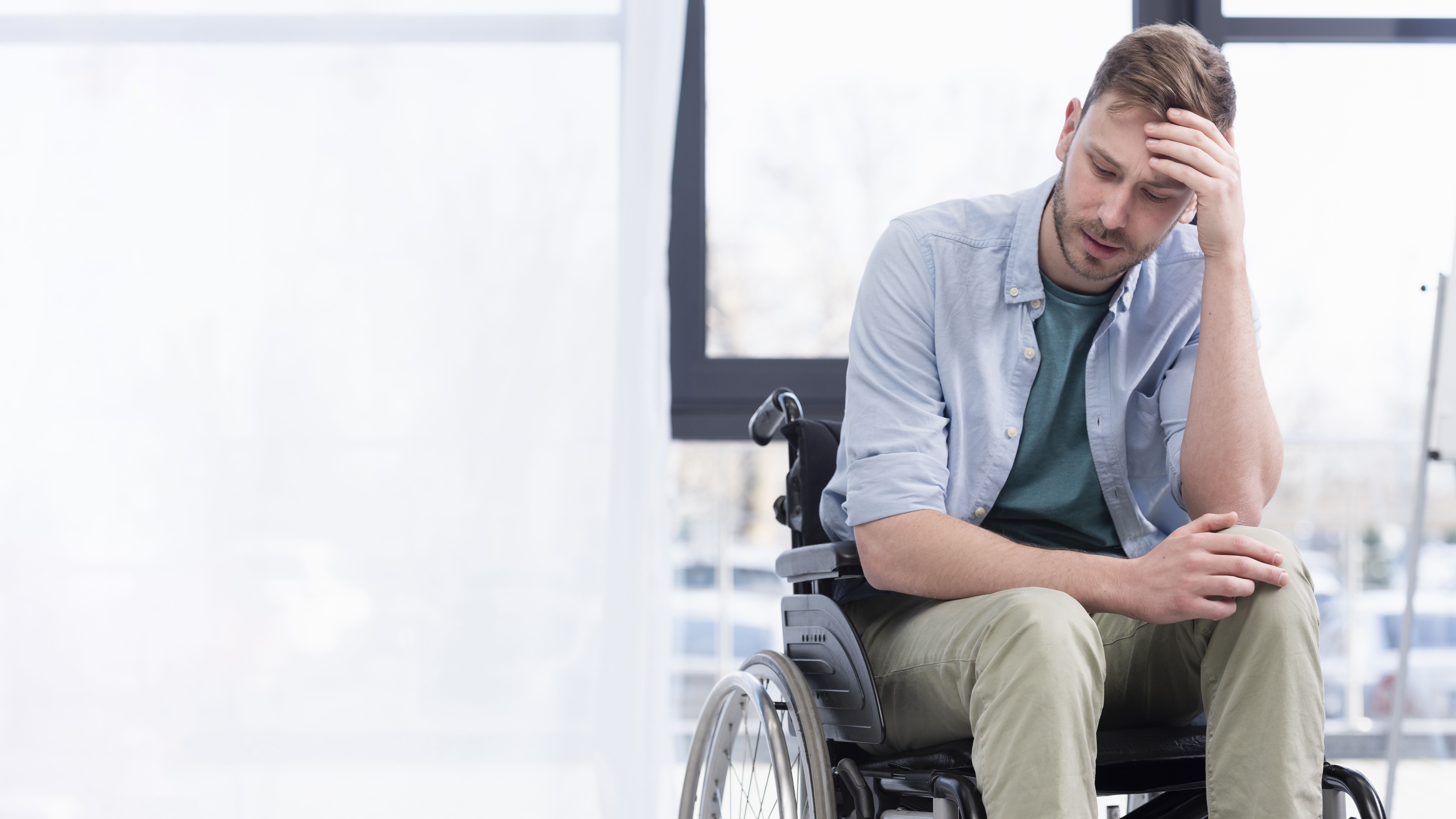 A realistic scene of a tired and emotionally distressed businessman sitting in a wheelchair after suffering a catastrophic injury, representing the life-changing impact of serious injuries handled by a Framingham catastrophic injury lawyer.