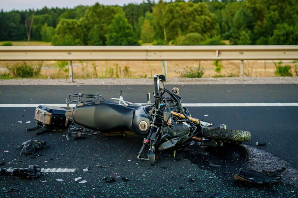 Motorcycle accident scene with damaged bike lying on highway after traffic collision.