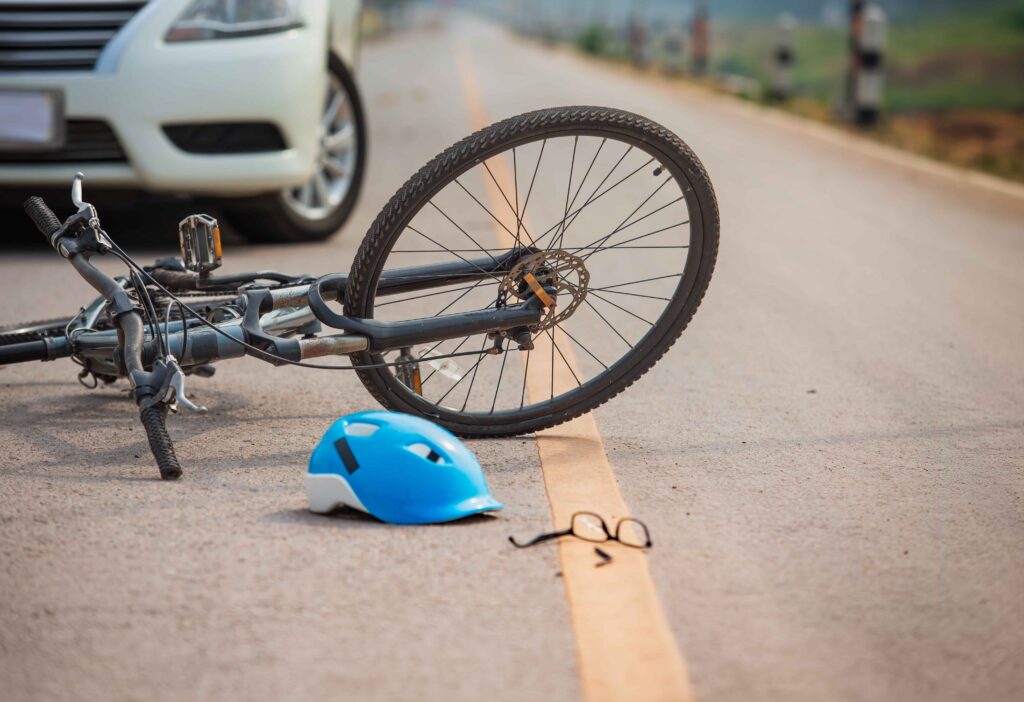 Bicycle lying on road with helmet and glasses after car and cyclist accident.