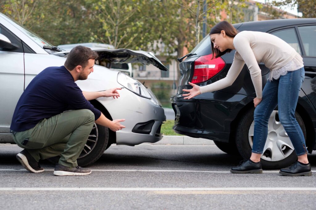 Drivers inspecting vehicle damage after a rear-end car accident in a parking lot.