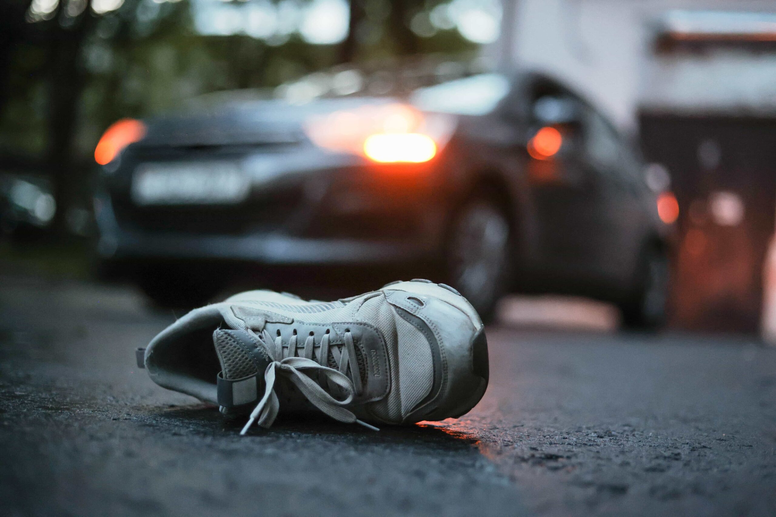 Single shoe lying on the road after a pedestrian car accident at night.